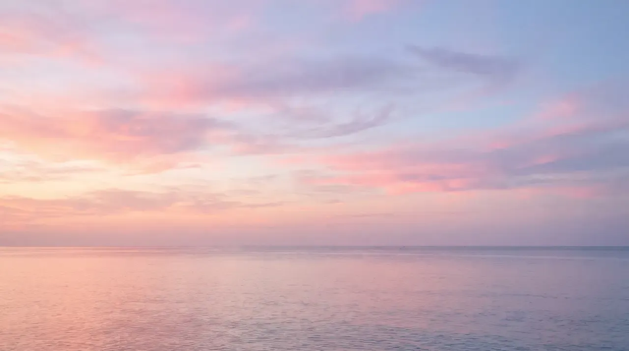 A calm sea meeting the horizon in early light